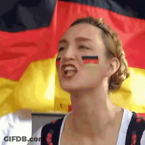 A Woman With Flags Painted On Her Face Stands In Front Of A German Flag GIF