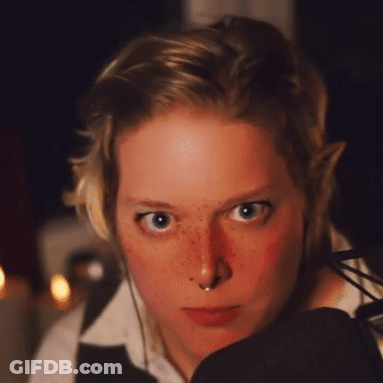 A Woman With Freckles And A Nose Ring Looks At The Camera GIF