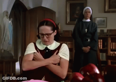 A Woman With Glasses And A Red Headband Is Sitting At A Table With A Nun Standing Behind Her GIF