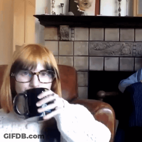 A Woman With Glasses Is Drinking From A Black Mug GIF