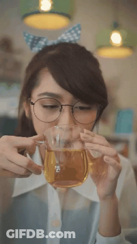 A Woman With Glasses Is Drinking From A Glass GIF