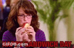 A Woman With Glasses Is Eating A Sandwich With The Words Happy Sandwich Day Above Her GIF