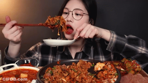 A Woman With Glasses Is Eating Food With Chopsticks GIF