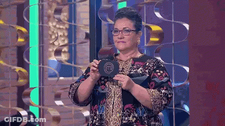 A Woman With Glasses Is Holding A Sign That Says M On It GIF
