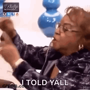 A Woman With Glasses Is Sitting At A Table With Her Hands In The Air And Says I Told Yall . GIF