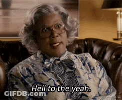 A Woman With Glasses Is Sitting On A Couch And Says Hell To The Yeah . GIF