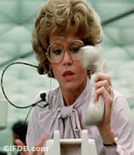 A Woman With Glasses Is Talking On A Telephone GIF