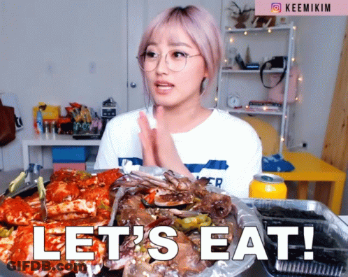 A Woman With Glasses Says Let 'S Eat GIF