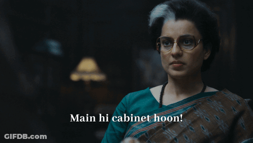 A Woman With Glasses Says Main Hi Cabinet Hoon In A Dark Room GIF