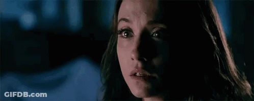 A Woman With Glowing Eyes Is Looking At The Camera In A Dark Room . GIF
