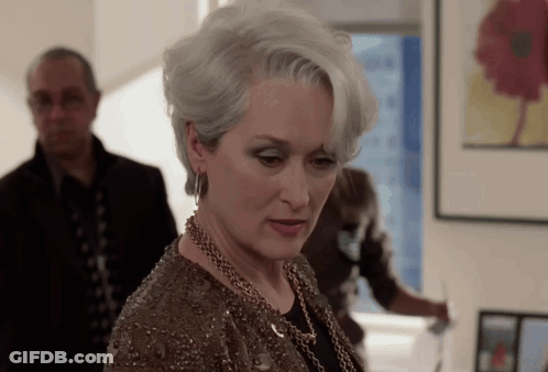 A Woman With Gray Hair And A Necklace Looks Down GIF