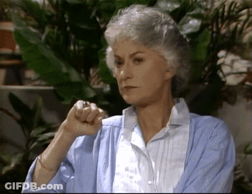 A Woman With Gray Hair Is Wearing A Blue Cardigan And White Shirt GIF