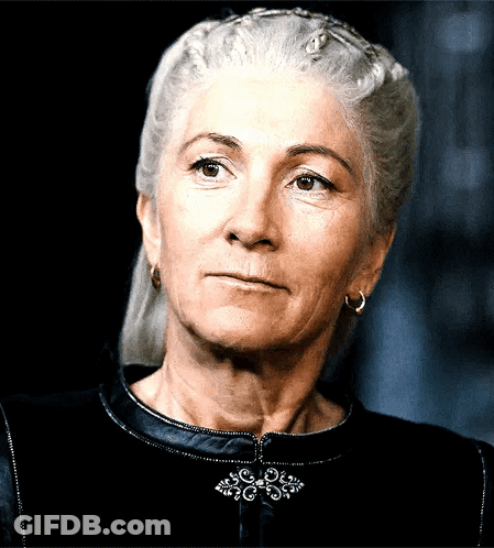 A Woman With Gray Hair Is Wearing Earrings And A Black Top GIF