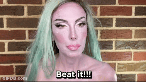 A Woman With Green Hair And White Paint On Her Face Says " Beat It " GIF
