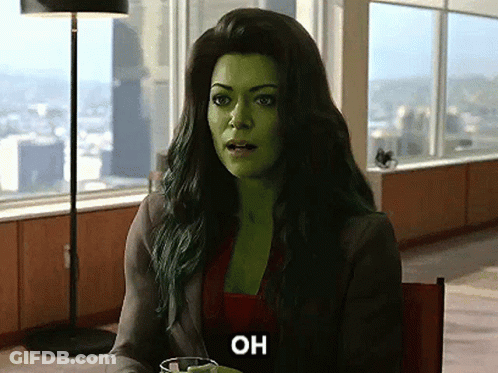 A Woman With Green Hair Is Sitting At A Table With A Glass Of Water And The Word Oh On Her Face . GIF