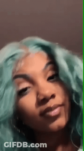 A Woman With Green Hair Is Smiling For The Camera . GIF