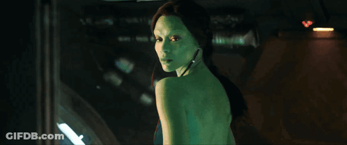 A Woman With Green Hair Is Standing In Front Of A Window GIF