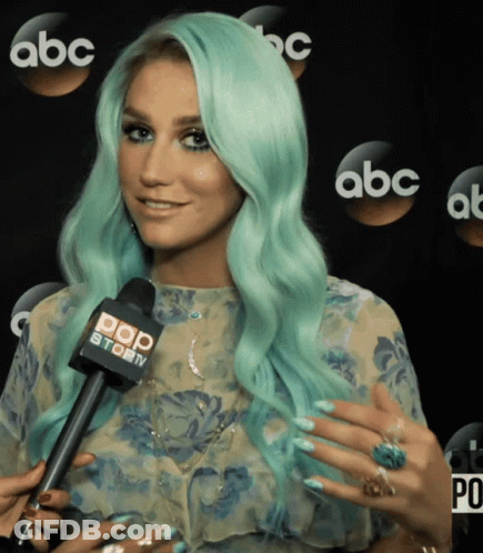 A Woman With Green Hair Is Talking Into A Microphone That Says Pop Story GIF