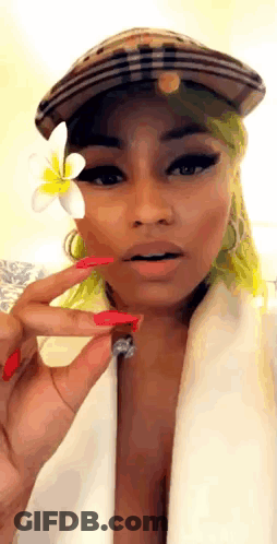 A Woman With Green Hair Is Wearing A Hat And Holding A Flower To Her Face . GIF