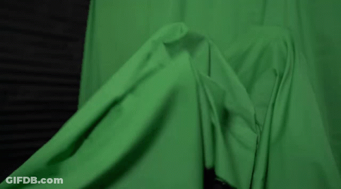 A Woman With Green Paint On Her Face Is Laying Under A Green Cloth . GIF