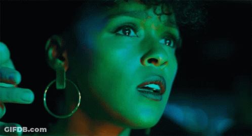 A Woman With Green Paint On Her Face Is Looking Up GIF