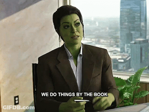 Woman With Green Face Paint Sitting At Desk Says We Do Things By The Book GIF