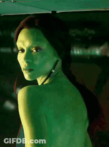 A Woman With Green Skin Is Looking Over Her Shoulder At The Camera GIF