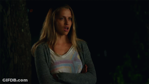 A Woman With Her Arms Crossed Is Wearing A Gray Cardigan GIF