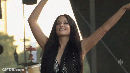 A Woman With Her Arms Outstretched Is Smiling In Front Of A Sign That Says ' I Love You ' GIF