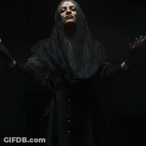 A Woman With Her Arms Outstretched Is Wearing A Black Veil And Black Gloves GIF