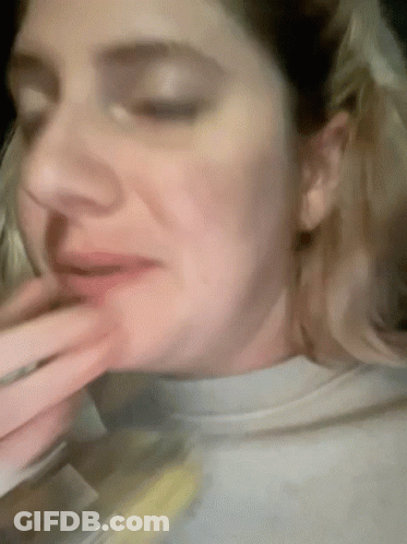 A Woman With Her Eyes Closed And Her Hand On Her Mouth GIF