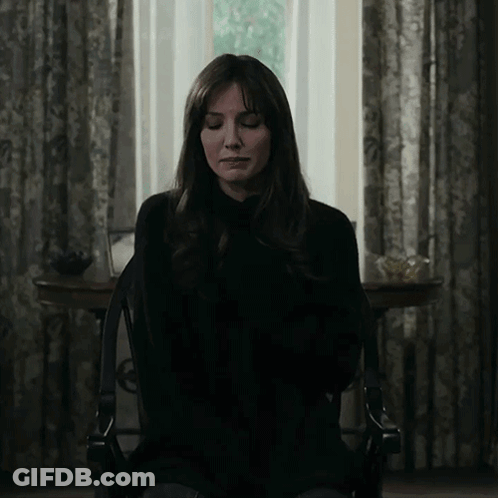 A Woman With Her Eyes Closed Is Sitting In A Chair In Front Of A Window GIF
