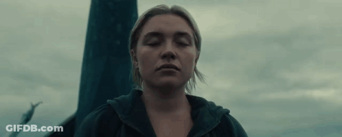 A Woman With Her Eyes Closed Is Standing In Front Of A Pole In The Dark . GIF