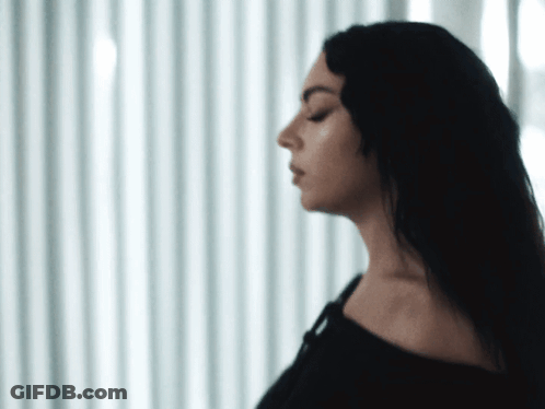 A Woman With Her Eyes Closed Is Standing In Front Of A Window GIF
