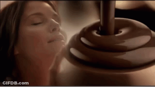 A Woman With Her Eyes Closed Smelling A Chocolate Covered Object GIF
