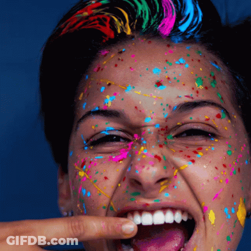 A Woman With Her Face Covered In Colorful Paint Is Smiling GIF