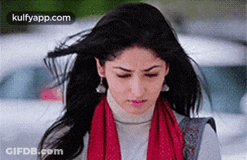 A Woman With Her Hair Blowing In The Wind Is Wearing A Red Scarf . GIF