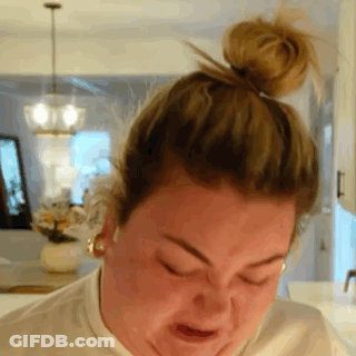 A Woman With Her Hair In A Bun Is Making A Face . GIF