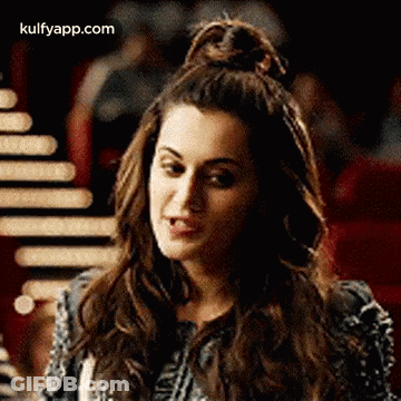 A Woman With Her Hair In A Bun Is Making A Funny Face And Looking At The Camera . GIF
