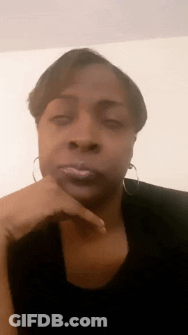 A Woman With Her Hand On Her Chin Is Wearing Hoop Earrings And A Black Shirt . GIF