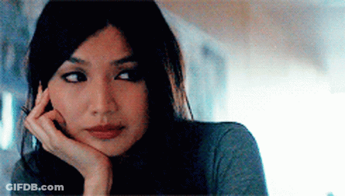 A Woman With Her Hand On Her Chin Looks At The Camera GIF