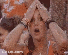 A Woman With Her Hands On Her Head Is Wearing A Necklace With A Cross On It GIF