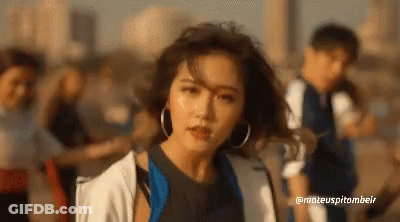 A Woman With Hoop Earrings Is Standing In Front Of A Group Of People .. GIF