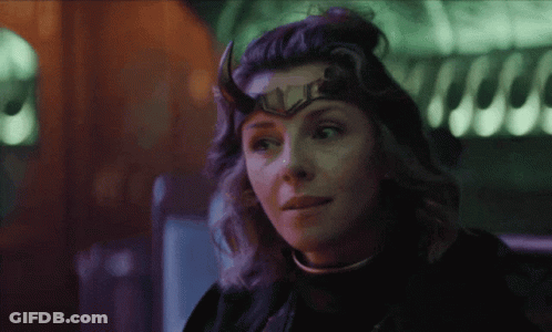 A Woman With Horns And A Crown On Her Head Looks At The Camera GIF