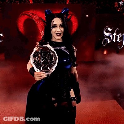 A Woman With Horns Is Holding A Trophy In Front Of A Sign That Says Stey GIF