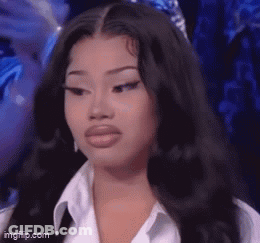 A Woman With Long Black Hair And A White Shirt Is Looking At The Camera . GIF