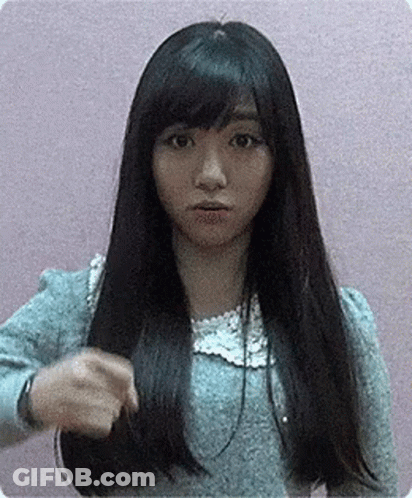 A Woman With Long Black Hair And Bangs Is Holding Her Hair In Her Hand . GIF