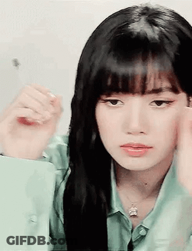 A Woman With Long Black Hair And Bangs Is Looking At Herself In The Mirror . GIF
