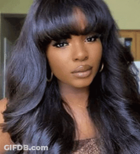 A Woman With Long Black Hair And Bangs Is Wearing Earrings . GIF