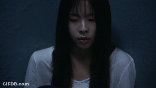 A Woman With Long Black Hair And Bangs Looks At The Camera GIF